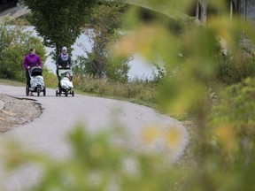Tracy Unger, right, with her son Coen, and Vallyn Schmidt, with her daughter (name withheld) walk along Spadina Crescent East near the University Bridge in Saskatoon, SK on Thursday, September 14, 2017. (Saskatoon StarPhoenix/Liam Richards)