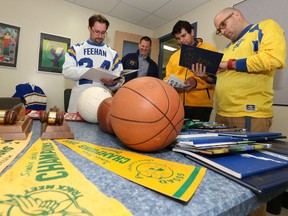 E.D. Feehan catholic high school graduates and teachers Dave Plaskett (left), Vice Principal Shaun Nechvatal, Stephen Ryan and Franco Soldo look through historic uniforms, trophies and year books brought out from storage in preparation for its 50th anniversary on Sept. 30.