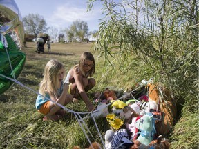 Khloie Erdman, left, and Aliyah Bloomquist visit a makeshift memorial near Dundonald School where a five-year-old boy died in a pond in Saskatoon, SK on Tuesday, September 12, 2017.