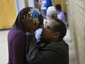 Hussein Elmmi holds his daughter Samira Elmmi on Tuesday during a group prayer at the Islamic Association of Saskatchewan mosque, where condolences were offered to the Elmmi family over the drowning death of five-year-old Ahmedsadiq. The boy drowned in a pond near Dundonald School on Monday. (Saskatoon StarPhoenix/Kayle Neis)