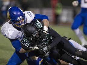 Huskies' receiver Yol Piok is hauled down after making a catch Saturday night at Griffiths Stadium.