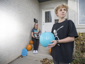 Katriona Mitchell, right, and her son James, who has a severe allergy, with a teal pumpkin and allergy friendly halloween treats in front of their home in Saskatoon, Sask. on Friday, Oct. 20, 2017.