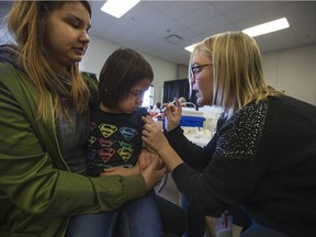 Tricia Clearsky (L) watches her daughter Sophia Brandon receive a flu shot during an Immunization clinic at Station 20 West in Saskatoon on Oct. 23, 2017.