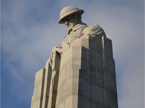 The elongated plinth of the Brooding Soldier monument transitions into the upper torso of a Canadian soldier, with his helmeted head bowed and his hands resting on his rifle in reverse arms.
