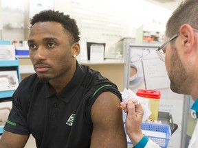 Saskatchewan Roughriders linebacker Jeff Knox Jr. gets a flu shot from pharmacist Brent Goeres at the Victoria Square Mall Shoppers Drug Mart.