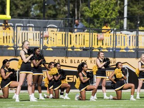 In this Saturday, Sept. 30, 2017 photo, five Kennesaw State University cheerleaders take a knee during the national anthem prior to a college football game against North Greenville, in Kennesaw, Ga. The group of cheerleaders from the college in Georgia say they'll take a knee in the stadium tunnel when the national anthem is played at Saturday's homecoming game since their university moved them off the field after an earlier demonstration. (Cory Hancock/Atlanta Journal-Constitution via AP)