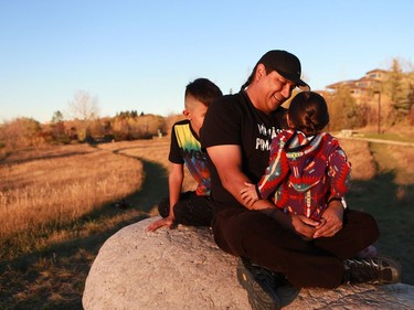 Randy Morin plays with his children, four-year-old daughter Kisay Morin and nine-year-old son Keesik Morin, on a rock at Gabriel Dumont Park in Saskatoon.