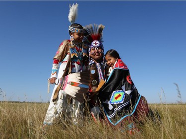 11-year-old Omiyosiw Nazbah Warren and six-year-old Kiihibaa Acahkos Warren hug their dad TJ Warren at Wanuskewin Heritage Park. Warren's parenting style keeps the family's indigenous heritage at the forefront, from dance to language to prayer.