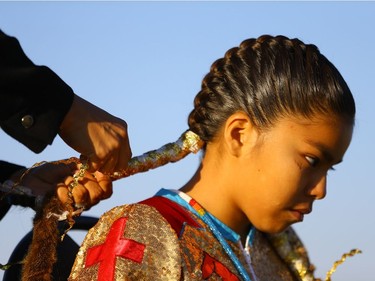 Dabney Warren braids her 11-year-old daughter Omiyosiw Nazbah Warren's hair before she dances at Wanuskewin Heritage Park.