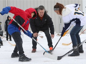 Committee chair Steve Hogle drops the puck for equipment recipients, who are playing their first game with new sticks donated Thursday.