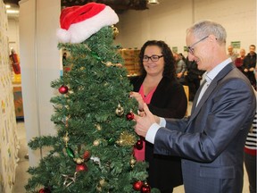 Laurie O'Connor, executive director of the Saskatoon Food Bank and Learning Centre, left, and PotashCorp's President and CEO Jochen Tilk place the first holiday stocking on the organization's "Tree of Plenty" at the campaign's launch at the Food Bank's warehouse on Nov. 20, 2017.