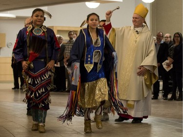 Most Rev. Mark Hagemoen, right, enters the Cathedral of the Holy Family church preceded by fancy dancer Sasha Stone, center, and jingle dancer Layla Stone, left, prior to his installation as Bishop of the Saskatoon Roman Catholic diocese in Saskatoon on Thursday, November 23, 2017.