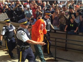 Gerald Stanley, hooded, is escorted past a gauntlet of media and Colton Boushie's supporters.