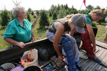 Cora Greer's summer staff Peyton McPhee and Jade Peters strap on baseball catcher padding to protect their legs from shearing knives at Mason Tree Farm.