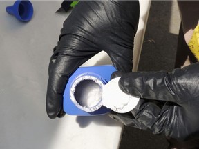 This RCMP file photo shows an officer opening a printer ink bottle containing the opioid carfentanil, imported from China, in Vancouver.