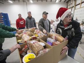 Paul Brace, age 13, helps with the distribution of food as part of the Secret Santa Foundation annual event, where over 800 families are welcomed to their warehouse where toys, books and nutritious food hampers are given for the holidays, in Saskatoon, on Wednesday, December 20, 2017.