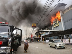 TOPSHOT - This photo taken on December 23, 2017 shows a firefighter standing in front of a burning shopping mall in Davao City on the southern Philippine island of Mindanao.  Thirty-seven people were believed killed in a fire that engulfed a shopping mall in the southern Philippine city of Davao, local authorities said on December 24.