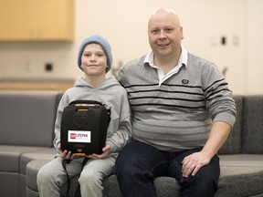 Ten-year-old Benjamin Fizzard, along with his father Sheldon, holds an AED inside Ecole Wascana Plains School in Regina. Benjamin suffered a cardiac incident at Wifrid Walker school and his family raised money to buy the device.