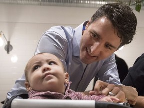 Prime Minister Justin Trudeau smiles towards a baby as speaks to people as they eat breakfast at Hometown Diner in Saskatoon on Friday, December 8, 2017.