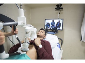 On the screen from right to left: researchers Scott Adams, Ivar Mendez and Paul Babyn demonstrate the long distance ultrasound imaging on a patient.