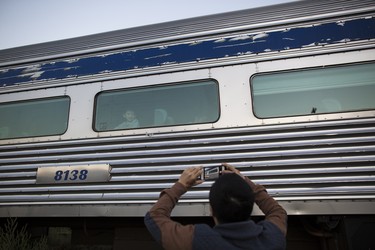 A man takes a photo of a boy on board a VIA Rail train during the summer of Canada's 150th anniversary.