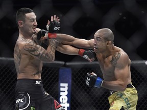 Max Holloway, left, is hit by Jose Aldo, of Brazil, during the first round of a UFC 218 featherweight mixed martial arts bout, early Sunday, Dec. 3, 2017, in Detroit. (AP Photo/Jose Juarez)