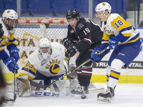 Saskatoon Blades goalie Nolan Maier looks out at a rebound as forward Bradly Goethals blocks Red Deer Rebels forward Josh Tarzwell during first-period WHL action in Saskatoon, SK on Friday, January 5, 2017.