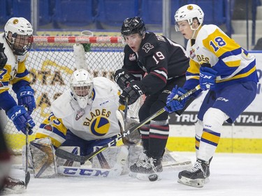 Saskatoon Blades goalie  Nolan Maier looks out at a rebound as forward  Bradly Goethals blocks Red Deer Rebels forward  Josh Tarzwell during first period WHL action in Saskatoon, SK on Friday, January 5, 2017.