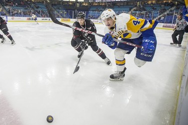 Saskatoon Blades forward  Chase Wouters moves the puck away from Red Deer Rebels forward  Reese Johnson in third period WHL action in Saskatoon, SK on Friday, January 5, 2017.