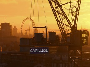 The sun sets behind a crane showing the branding of British construction company Carillion at a building site in central London.