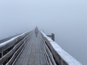 A woman walks through the fog on the train bridge in Saskatoon, SK on January 21, 2018.
