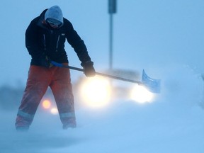 A man battles blowing snow in an attempt to clear the sidewalk in front of Saint Kateri Tekakwitha Catholic School in Saskatoon, January 30, 2018.