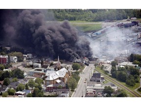 FILE - In this July 6, 2013, file photo, smoke rises from railway cars from now-defunct Montreal, Maine & Atlantic Railways company that were carrying crude oil after derailing in downtown Lac Megantic, Quebec, Canada