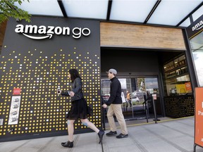 FILE - In this Thursday, April 27, 2017, file photo, people walk past an Amazon Go store in Seattle. Amazon Go shops are convenience stores that don't use cashiers or checkout lines, but use a tracking system that of sensors, algorithms, and cameras to determine what a customer has bought.