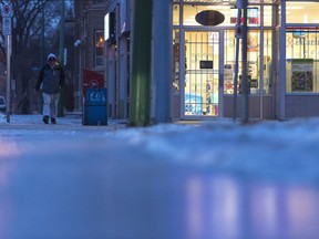 A man walks as light from Lorne Drugs reflects off the surface of smooth ice covering the sidewalk. Freezing rain fell yesterday during the afternoon, causing slippery conditions walking and driving conditions.