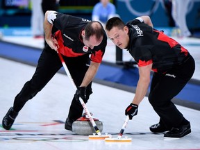 Canada's Ben Hebert (R) brushes with his teammate Brent Laing in front of the stone during the curling men's round robin session between Canada and South Korea during the Pyeongchang 2018 Winter Olympic Games at the Gangneung Curling Centre in Gangneung on February 16, 2018.