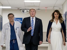 President Donald Trump, center, accompanied by and first lady Melania Trump, right, and Dr. Igor Nichiporenko, left, speak to reporters while visiting with medical staff at Broward Health North in Pompano Beach, Fla., Friday, Feb. 16, 2018.