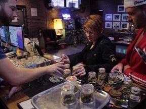 Budtender Phillip Courdery, left, discusses different varieties of marijuana with Marissa Toia, of Kansa City, Mo., and Mike Tebo, of San Diego, Calif., as Toia decides which to purchase at Cannabis Station dispensary on Monday, April 24, 2017 in downtown Denver. As the race to produce enough cannabis for the soon-to-be-legal market gets increasingly crowded, licensed producers are setting their sights on the next frontier in the race for maximum pot profitability: developing retail stores.