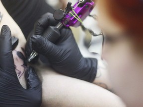 A tattoo artist works on a client in in Kenai, Alaska in a March 14, 2105 file photo. Setting up tattoo parlours and needle-exchange programs in federal prisons would help reduce hepatitis C rates, the Correctional Service tells Public Safety Minister Ralph Goodale.