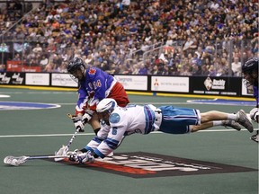 Dan Dawson of the Rochester Nighthawks  goes flying between Bob Marshall and Brodie Merrill of the Toronto Rock in a National Lacrosse League at the Air Canada Centre in Toronto, Ont. on Friday April 3, 2015.