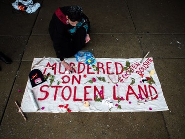 Barbara Manitowabie lays flowers on a memorial for Colten Boushie as protesters gather in Nathan Phillips Square in Toronto on Saturday, Feb. 10, 2018.