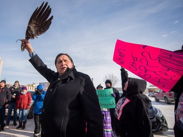 Colten Boushie's uncle Alvin Baptiste raises an eagle's wing as demonstrators gathered outside of the courthouse in North Battleford, Sask., on Saturday, February 10, 2018.