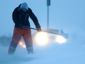 A man battles blowing snow in an attempt to clear the sidewalk in front of Saint Kateri Tekakwitha Catholic School in Saskatoon, SK on January 30, 2018.
