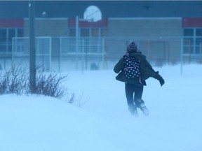 A student runs to school across a field of blowing snow in Saskatoon, SK on January 30, 2018.