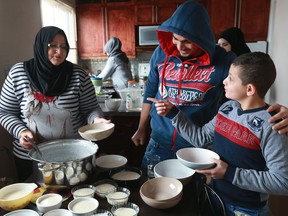 Houda Dibou prepares a dessert for her family, with help from her sons Ahmed Akraa and Mohammad Akraa. The Akraa family and their sponsorship group are part of a new documentary series airing on City TV called Bridging Borders.