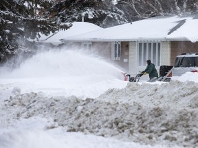 People clear snow along 33rd Street West in Saskatoon, SK on Monday, March 5, 2018.