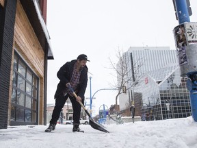 Troy Miller, a manager at El Coyote Bar sweeps the street during a snowy day in Saskatoon on Saturday, March 3, 2018.