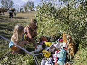 (L to R) Khloie Erdman and Aliyah Bloomquist stand around a makeshift memorial by Dundonald School after a five-year-old boy died in a nearby pond in Saskatoon, SK on Tuesday, September 12, 2017.