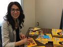 Calyn Stange est photographiée avec des exemplaires du livre pour enfants qu'elle a écrit, Are You Hungry?  Les livres ont été écrits en cri/anglais, déné/anglais et michif/anglais et seront distribués aux enfants de 18 mois dans le nord de la Saskatchewan.