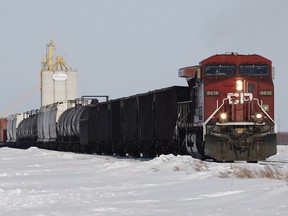Grain and oil rail cars pass by a grain elevator in Rosser, Man.